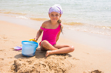 Image showing A child plays in the sand shovel and bucket on the sea shore