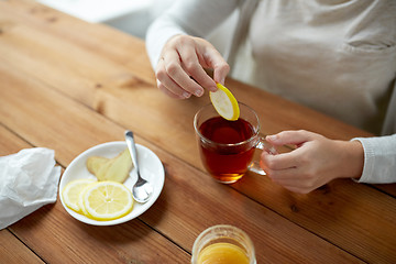 Image showing close up of woman adding lemon to tea cup