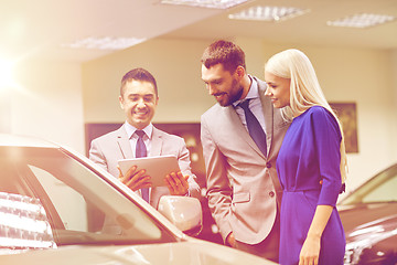 Image showing happy couple with car dealer in auto show or salon