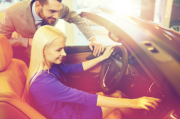 Image showing happy couple buying car in auto show or salon