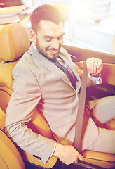 Image showing happy man sitting in car at auto show or salon