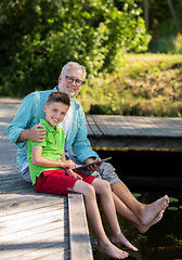 Image showing grandfather and boy with tablet pc on river berth