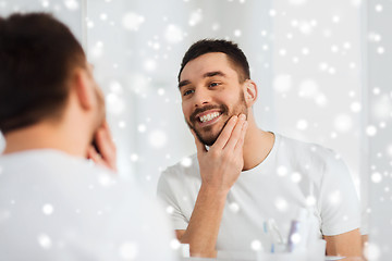 Image showing happy young man looking to mirror at home bathroom