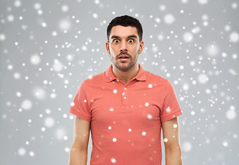 Image showing surprised man in polo t-shirt over snow background