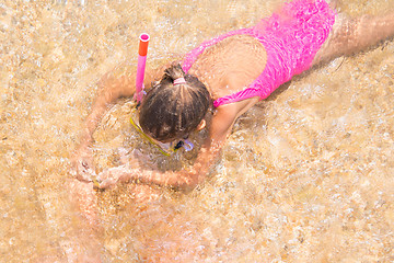 Image showing Girl in the mask and tube swims under water in shallow water