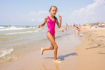 Image showing Seven-year girl runs on the beach from the sea
