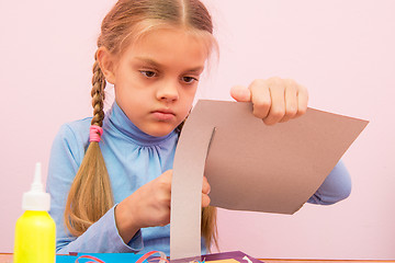 Image showing The child cuts a strip of cardboard in the classroom