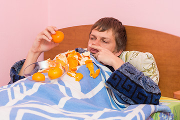 Image showing A man who lies in bed sick of mandarins