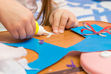 Image showing Girl sticks two strips, making crafts out of colored paper