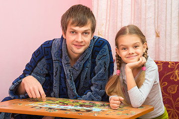 Image showing Dad and daughter in the frame looked sitting at the table and collecting puzzles