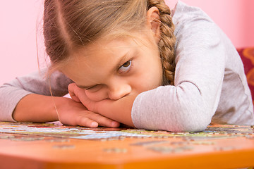 Image showing The girl was very tired assemble a picture from puzzles