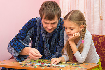 Image showing Dad and daughter enthusiastically collect picture of puzzles