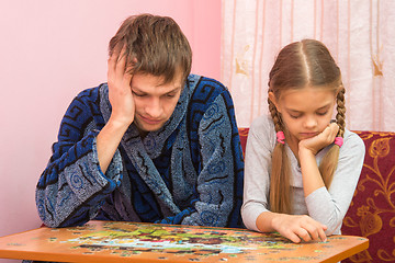 Image showing My daughter collects a picture from puzzles, tired dad sitting next