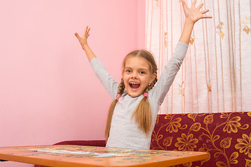Image showing Girl happily raised his hands up collecting picture of puzzles