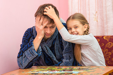 Image showing Daughter fun soothes tired dad who collect puzzles