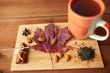 Image showing cup of tea, maple leaf and almond on wooden board