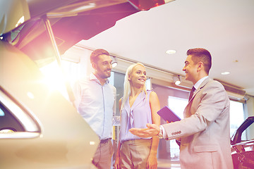 Image showing happy couple with car dealer in auto show or salon