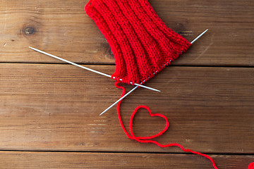 Image showing knitting needles and thread in heart shape on wood