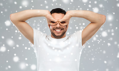 Image showing man making finger glasses over snow