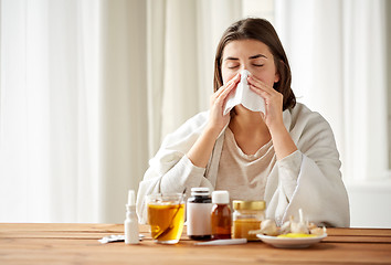 Image showing sick woman with medicine blowing nose to wipe