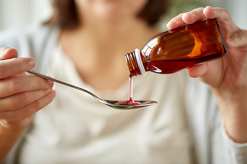 Image showing woman pouring medication from bottle to spoon