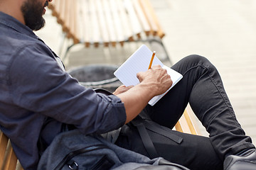 Image showing close up of man writing to notebook on city street
