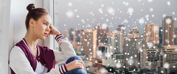 Image showing sad pretty teenage girl looking through window