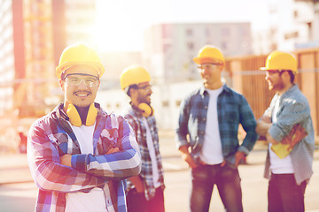 Image showing group of smiling builders in hardhats outdoors