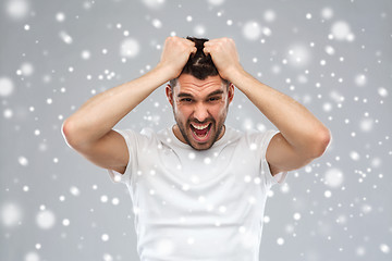 Image showing crazy shouting man in t-shirt over snow background