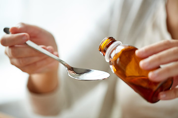 Image showing woman pouring medication from bottle to spoon