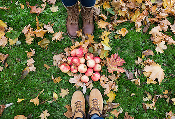 Image showing feet in boots with apples and autumn leaves