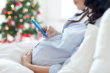 Image showing close up of pregnant woman with smartphone in bed