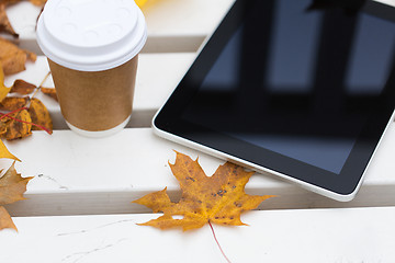 Image showing tablet pc and coffee cup on bench in autumn park