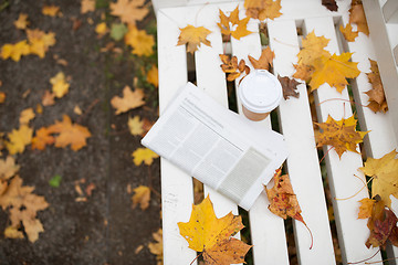 Image showing newspaper and coffee cup on bench in autumn park