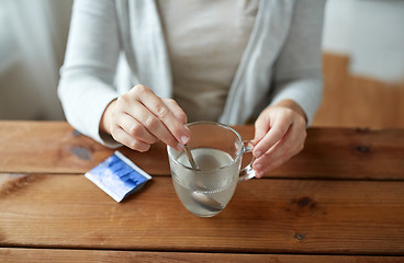 Image showing woman stirring medication in cup with spoon