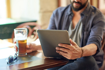 Image showing close up of man with tablet pc and beer at pub