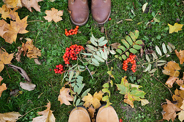 Image showing feet in boots with rowanberries and autumn leaves