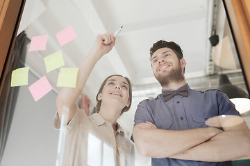 Image showing happy creative team writing on blank office glass