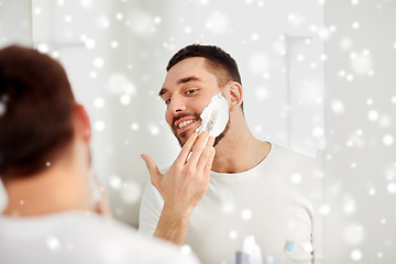 Image showing happy man applying shaving foam at bathroom mirror