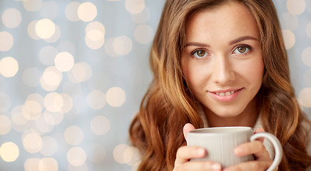 Image showing close up of happy woman with tea cup over lights