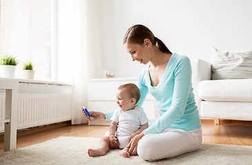 Image showing happy mother showing smartphone to baby at home