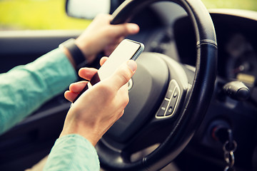Image showing close up of man hand with smartphone driving car