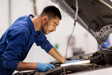 Image showing mechanic man with lamp repairing car at workshop