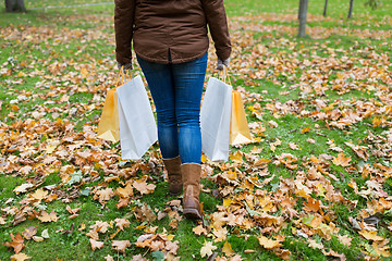 Image showing woman with shopping bags walking along autumn park