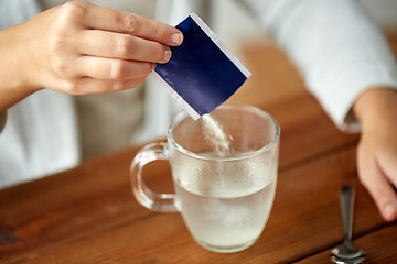 Image showing woman pouring medication into cup of water