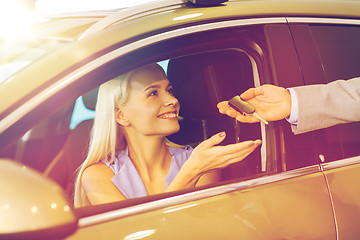 Image showing happy woman getting car key in auto show or salon