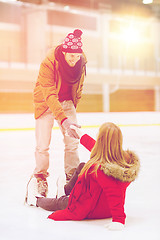 Image showing man helping women to rise up on skating rink