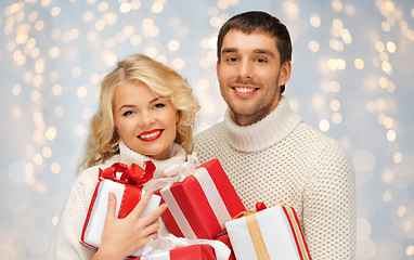 Image showing smiling man and woman with presents over lights