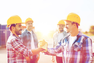 Image showing group of smiling builders shaking hands outdoors