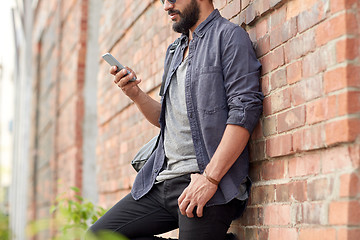 Image showing close up of man texting on smartphone in city